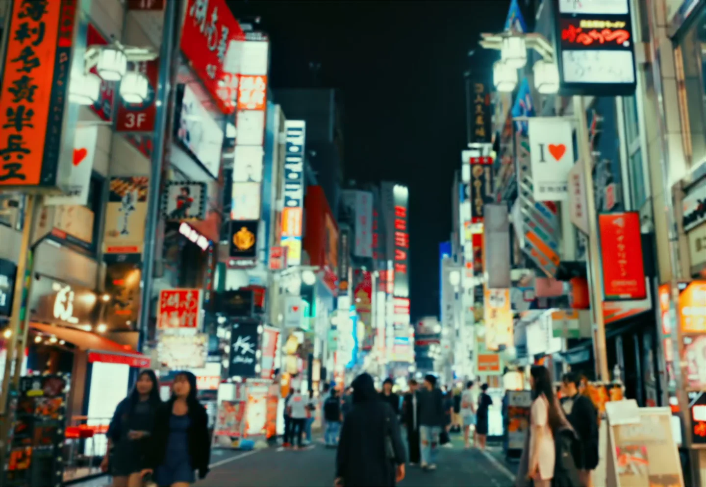 Mennesker og lysende skilt i en gate i Tokyo.